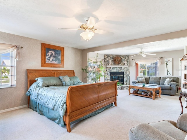 bedroom featuring light carpet, a textured ceiling, a fireplace, and ceiling fan