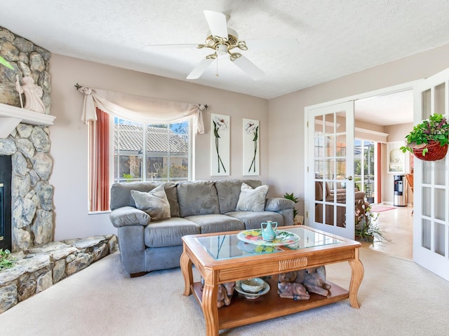 carpeted living room featuring a textured ceiling, ceiling fan, french doors, and a fireplace