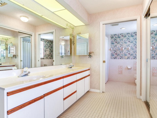 bathroom featuring toilet, tile floors, double sink, and vanity with extensive cabinet space