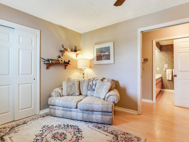 living room featuring a textured ceiling, light hardwood / wood-style floors, and ceiling fan