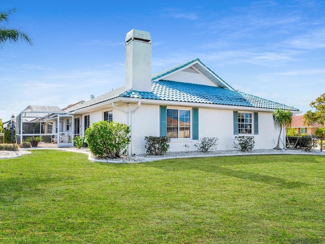 rear view of house with a lanai and a lawn