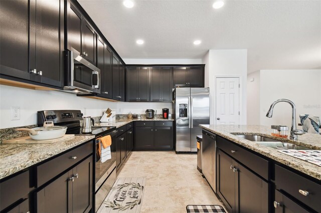 kitchen featuring sink, light stone counters, stainless steel appliances, and light tile patterned floors