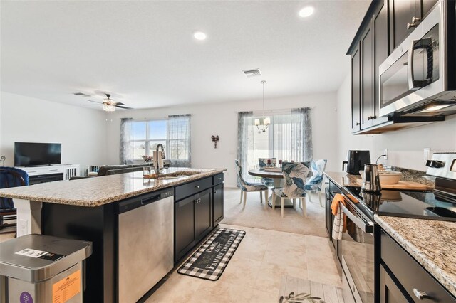 kitchen with range, light tile patterned floors, ceiling fan with notable chandelier, an island with sink, and dishwasher