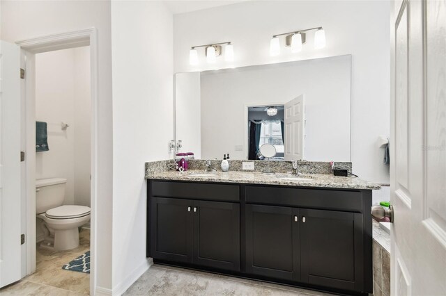 bathroom featuring dual vanity, toilet, and tile patterned floors