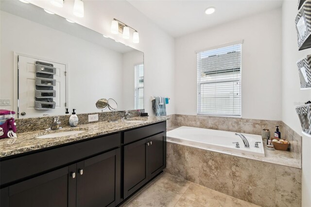 bathroom featuring tiled bath, tile patterned floors, and dual bowl vanity