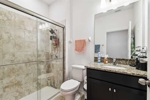 bathroom with a shower with shower door, toilet, and vanity