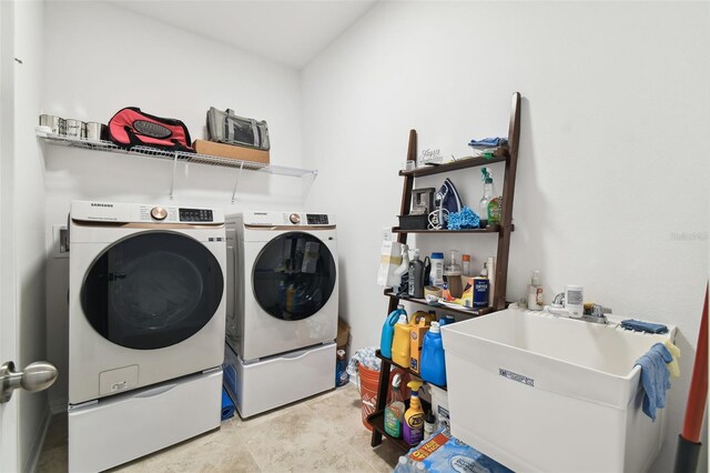 clothes washing area featuring light tile patterned flooring, washing machine and clothes dryer, and sink