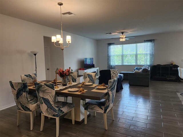 dining room with dark hardwood / wood-style flooring and ceiling fan with notable chandelier