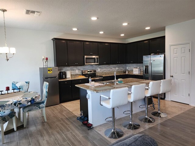 kitchen featuring a breakfast bar area, tasteful backsplash, stainless steel appliances, and light hardwood / wood-style floors