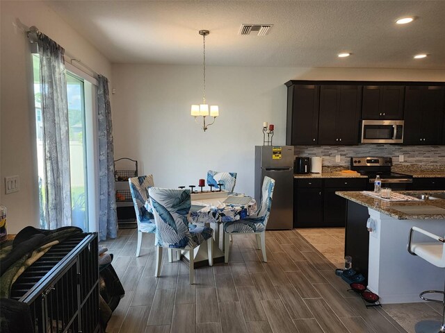 kitchen featuring stainless steel appliances, decorative backsplash, light stone countertops, a textured ceiling, and hardwood / wood-style flooring