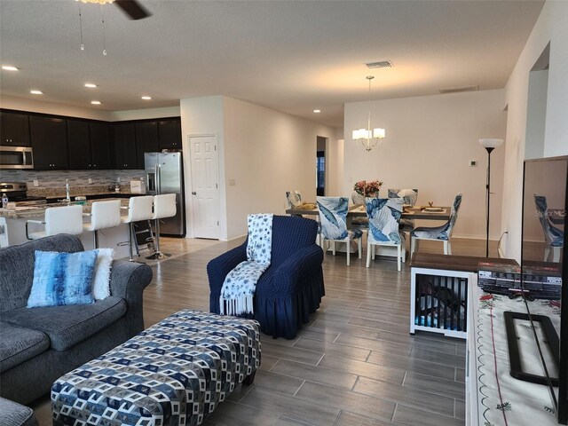 living room with ceiling fan with notable chandelier and sink