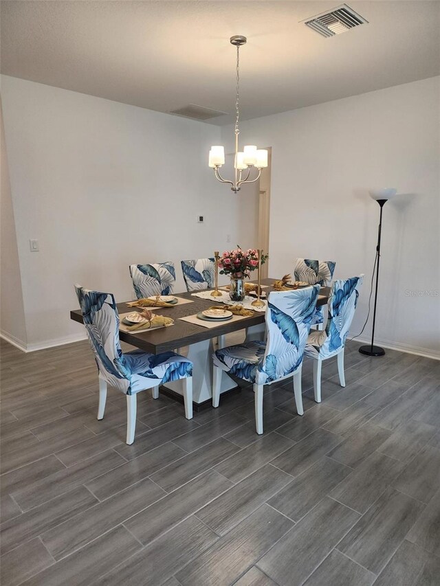 dining room with wood-type flooring and an inviting chandelier