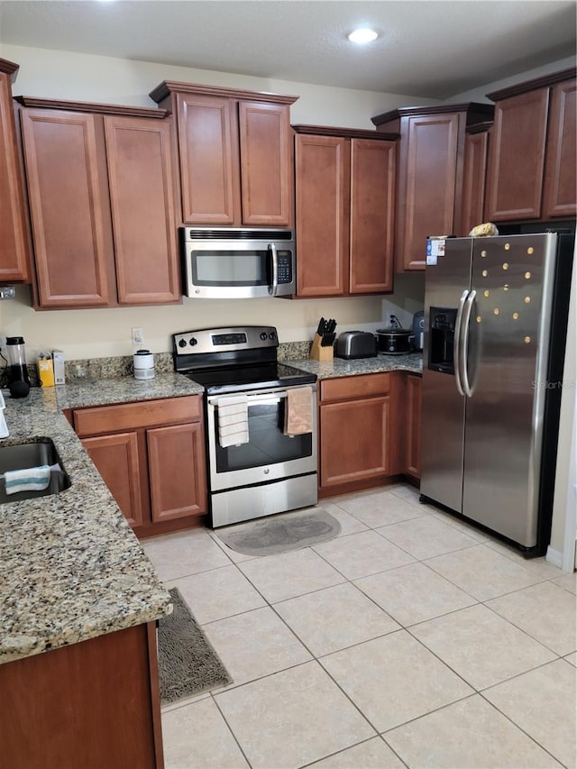 kitchen featuring sink, appliances with stainless steel finishes, light stone counters, and light tile flooring