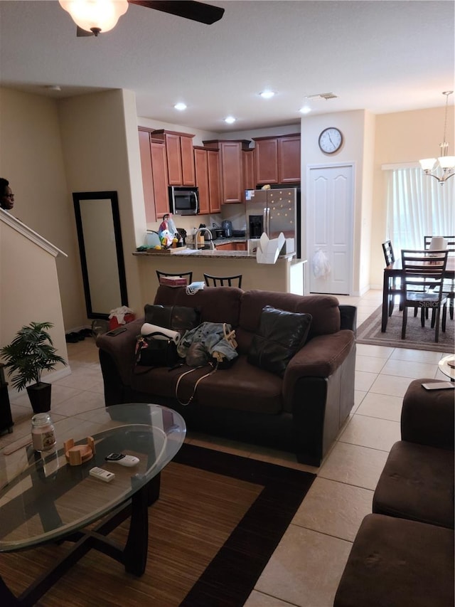 living room featuring light tile floors and ceiling fan with notable chandelier