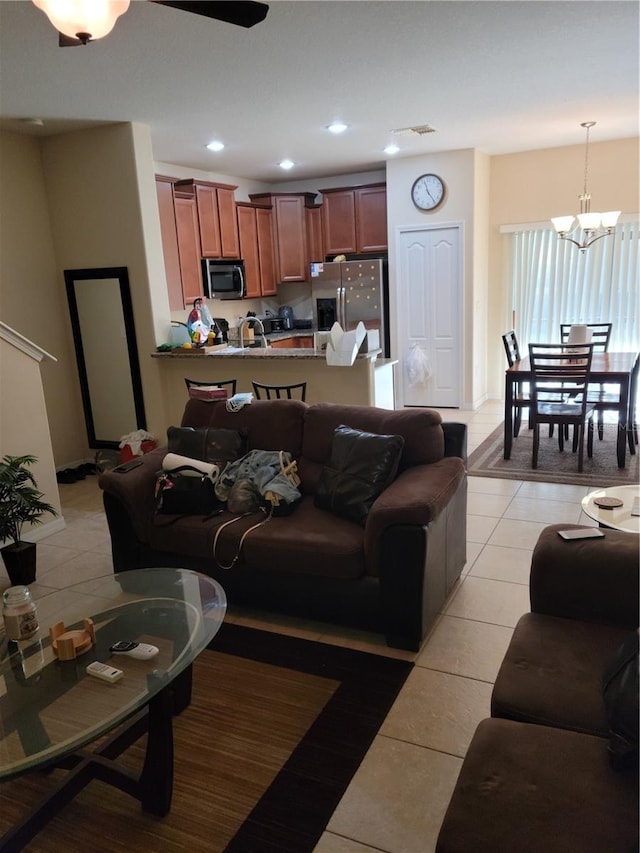 tiled living room with ceiling fan with notable chandelier