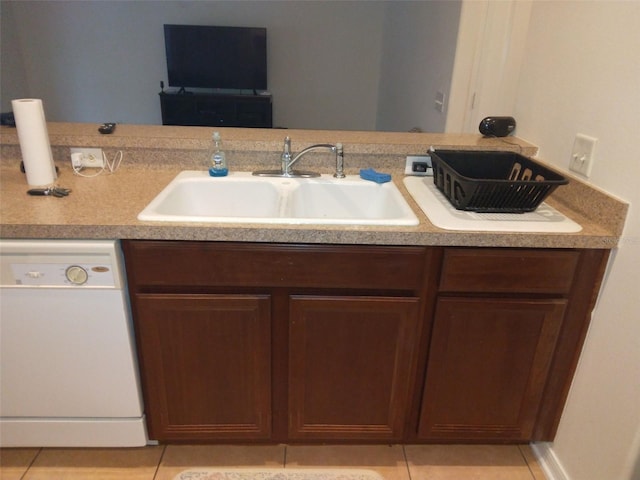 interior space featuring dark brown cabinetry, dishwasher, sink, and light tile flooring