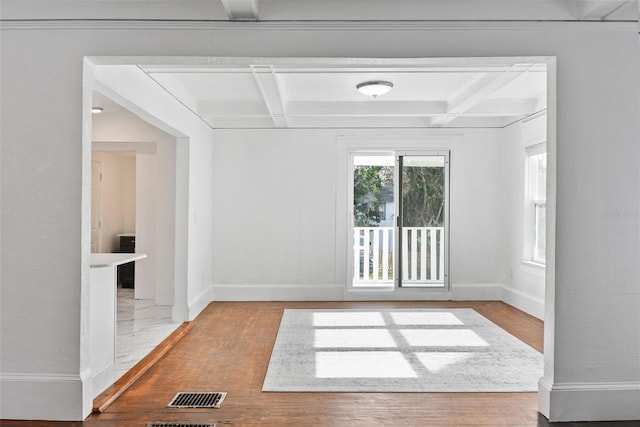 unfurnished room featuring coffered ceiling, light hardwood / wood-style floors, and beamed ceiling