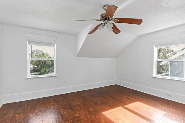 additional living space with ceiling fan, vaulted ceiling, dark wood-type flooring, and a textured ceiling