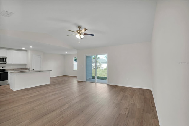 interior space featuring light hardwood / wood-style floors, stainless steel appliances, ceiling fan, white cabinetry, and a kitchen island with sink