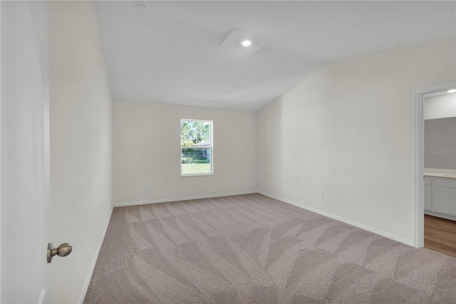 empty room featuring vaulted ceiling and light colored carpet