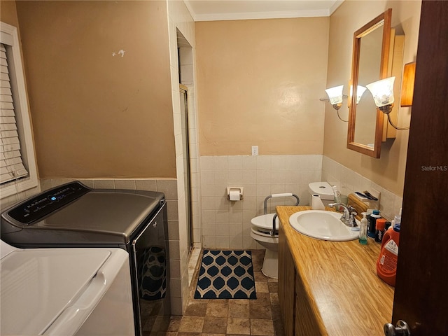 laundry room with crown molding, sink, tile walls, and washing machine and clothes dryer