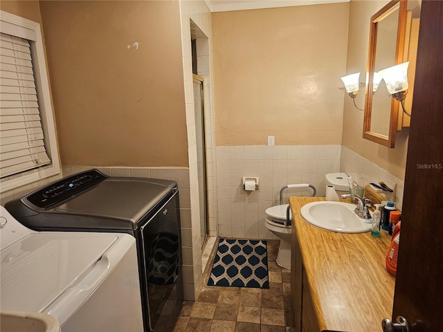 clothes washing area with tile walls, sink, and washing machine and clothes dryer