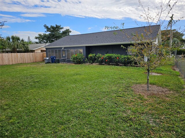 rear view of property with a sunroom and a lawn