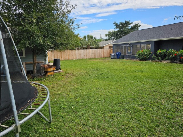 view of yard with a trampoline and a sunroom