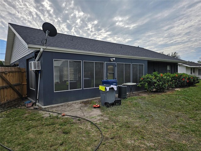 back of house with a wall mounted air conditioner and a lawn