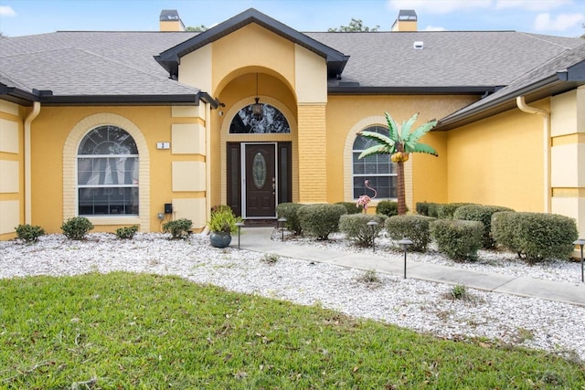 view of exterior entry featuring a lawn