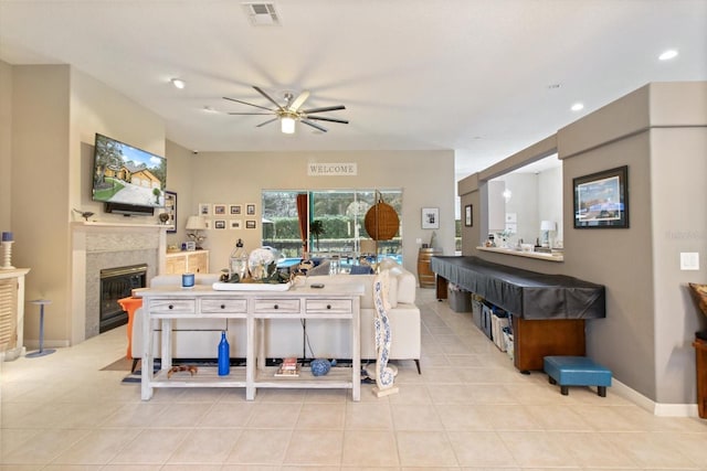 interior space with light tile floors, a tile fireplace, and ceiling fan