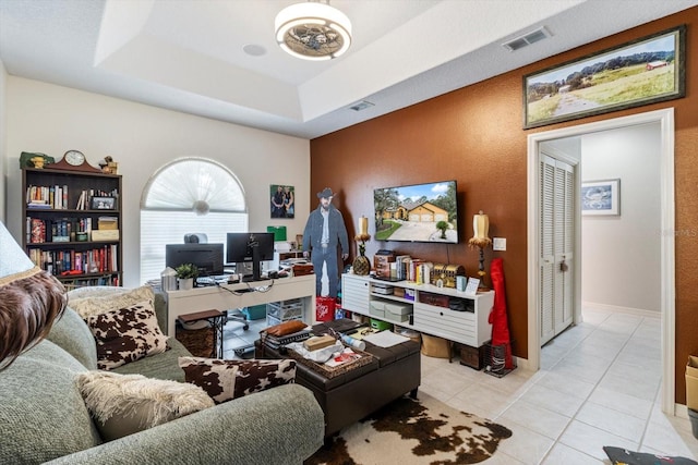 living room with a tray ceiling and light tile floors