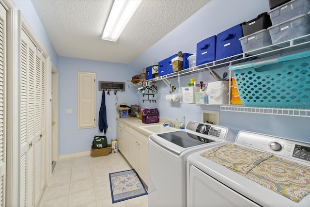 laundry room with a textured ceiling, cabinets, separate washer and dryer, and light tile floors