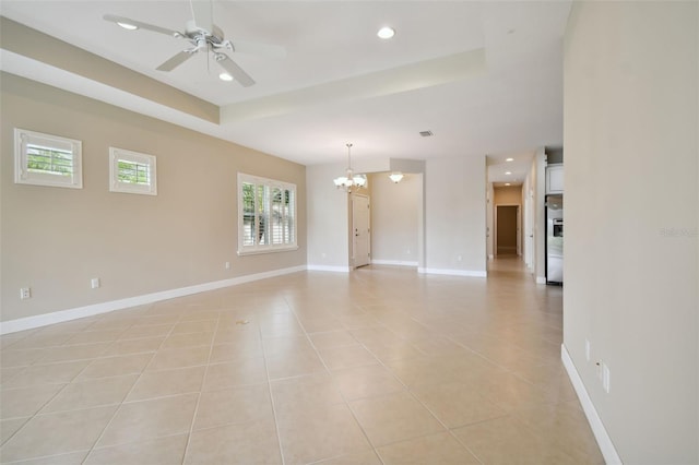 unfurnished room with a raised ceiling, ceiling fan with notable chandelier, and light tile patterned floors