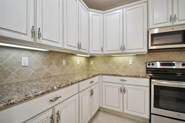 kitchen featuring light stone counters, backsplash, stainless steel appliances, and white cabinets