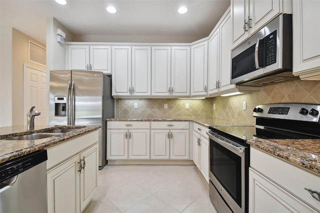 kitchen with appliances with stainless steel finishes, sink, white cabinets, and dark stone counters