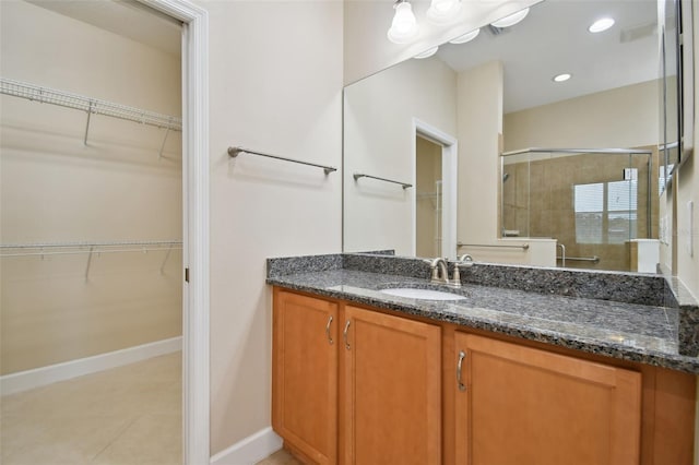 bathroom with a shower with door, vanity, and tile patterned flooring