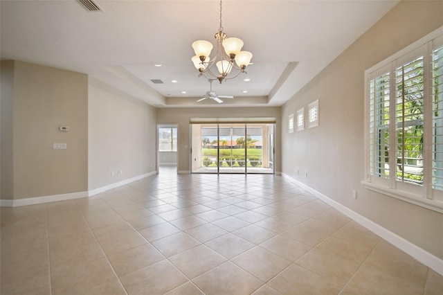 tiled empty room with ceiling fan with notable chandelier and a tray ceiling