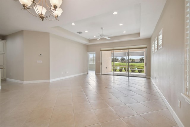 unfurnished room with a tray ceiling, ceiling fan with notable chandelier, and light tile patterned floors