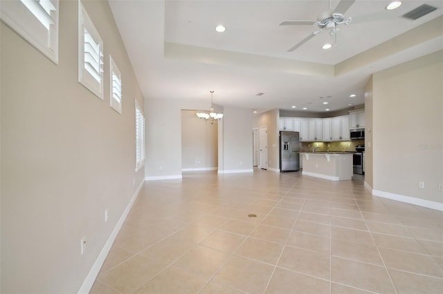 unfurnished living room featuring ceiling fan with notable chandelier and light tile patterned floors