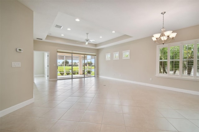 tiled empty room with a tray ceiling and ceiling fan with notable chandelier