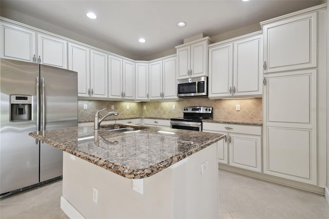 kitchen with white cabinetry, sink, stainless steel appliances, and a center island with sink