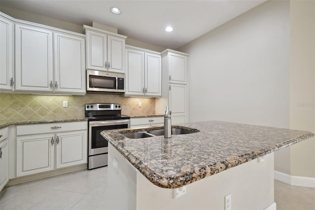 kitchen featuring stainless steel appliances, an island with sink, sink, and white cabinetry