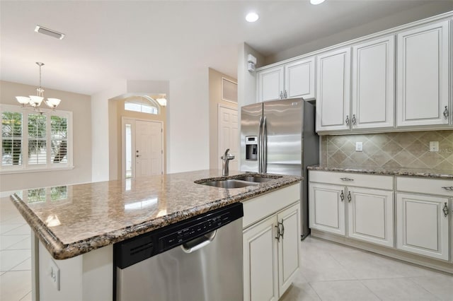 kitchen with appliances with stainless steel finishes, a notable chandelier, a kitchen island with sink, decorative backsplash, and white cabinets