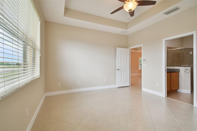 unfurnished bedroom featuring ceiling fan, connected bathroom, a raised ceiling, and light tile patterned floors