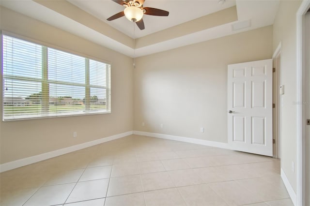 tiled spare room featuring ceiling fan and a raised ceiling