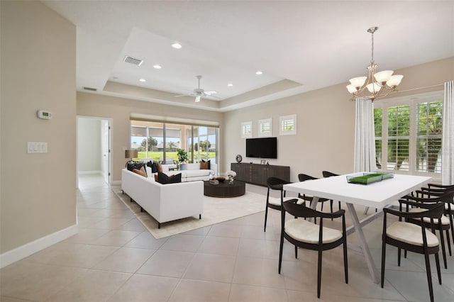 living room with light tile patterned floors, ceiling fan with notable chandelier, and a raised ceiling