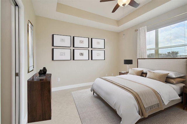 bedroom featuring light tile patterned floors, a raised ceiling, and ceiling fan