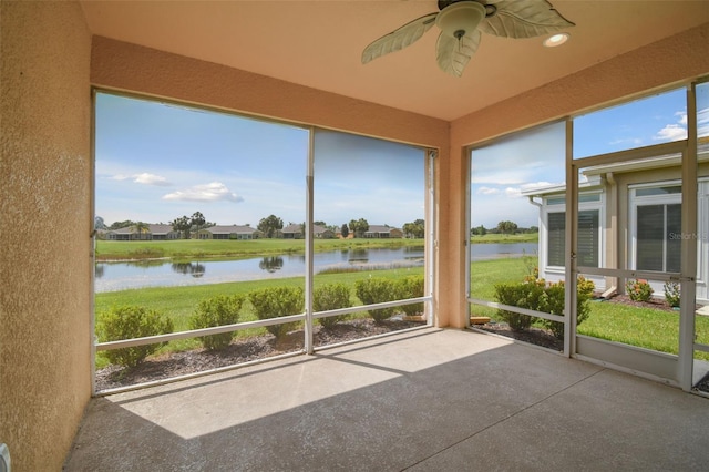 unfurnished sunroom featuring a water view and ceiling fan