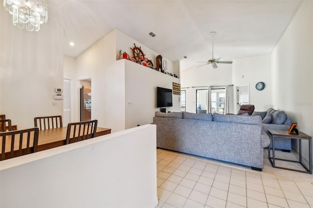 tiled living room featuring high vaulted ceiling and ceiling fan with notable chandelier